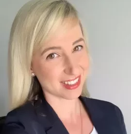 Frau mit blondem Haar und dunklem Blazer lächelt