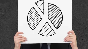 Person hält ein Poster mit handgezeichnetem Kuchendiagramm vor dem Gesicht.