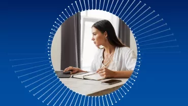 Frau arbeitet konzentriert am Schreibtisch mit Laptop und Notizbuch.