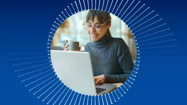 Frau mit Brille trinkt Kaffee und arbeitet am Laptop.