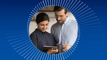 Zwei Personen nutzen ein Tablet und lächeln.