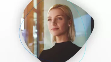 Porträt einer lächelnden Frau mit blondem Haar in einem hellen Raum.