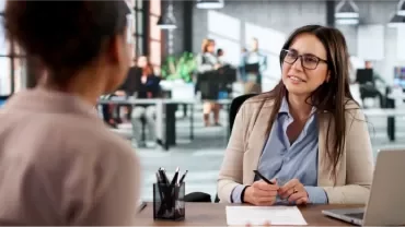 Zwei Frauen führen in einem modernen Büro ein professionelles Bewerbungsgespräch.