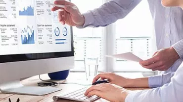 Zwei Personen diskutieren Daten auf einem Monitor.