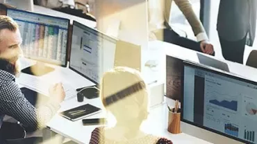 Geschäftsleute arbeiten am Computerbildschirm mit Diagrammen.