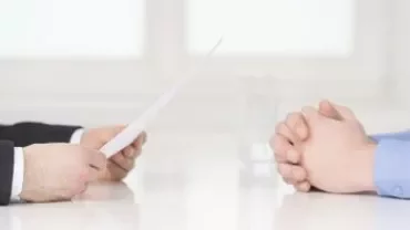 Zwei Personen bei einem Gespräch, eine hält ein Dokument.