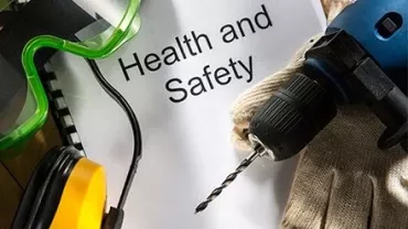 Bohrmaschine, Schutzbrille, Handschuhe und Papier mit 'Gesundheit und Sicherheit'.