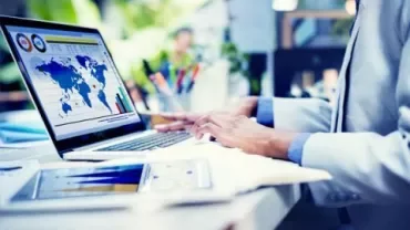 Person arbeitet am Laptop mit Weltkarte auf dem Bildschirm