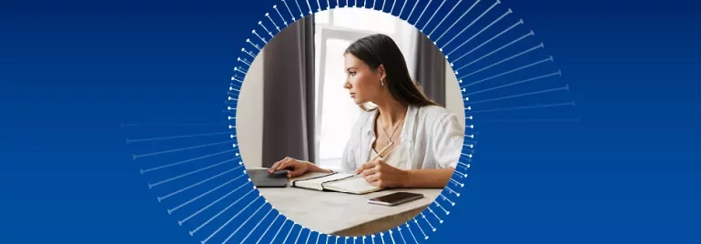 Frau arbeitet konzentriert am Schreibtisch mit Laptop und Notizbuch.
