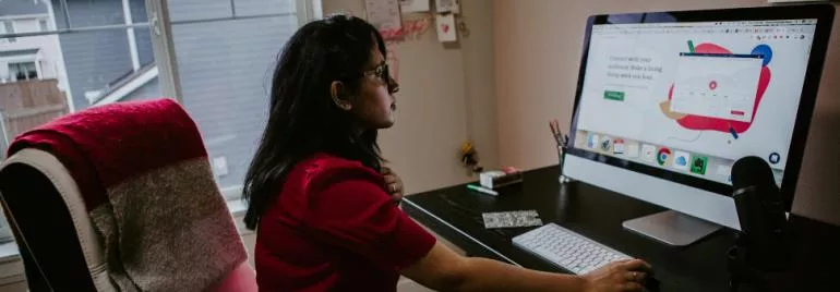 Frau arbeitet am Schreibtisch mit Computerbildschirm.