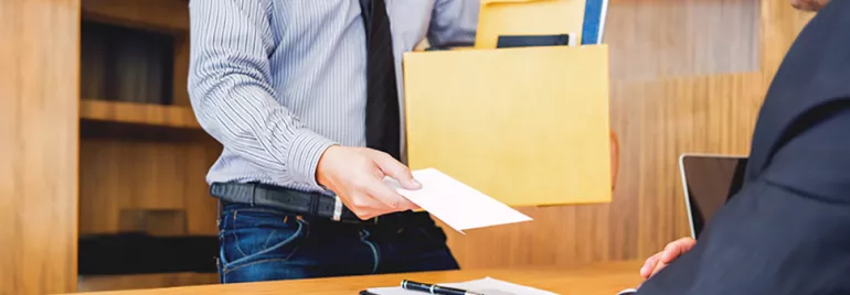 Mann überreicht Umschlag an sitzende Person.