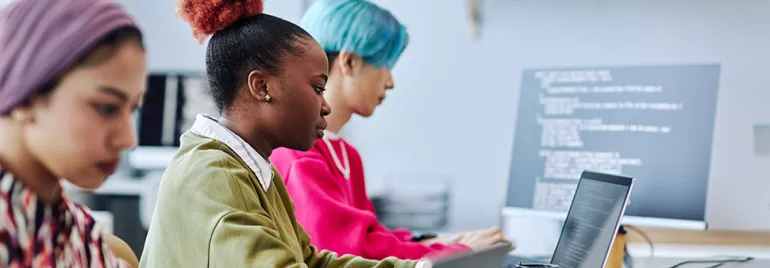 Drei Personen arbeiten an Laptops in einem modernen Büro.
