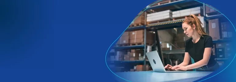 Frau sitzt am Computer in einer Lagerumgebung