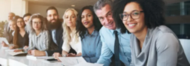 Gruppe von diversen Menschen an einem Konferenztisch.
