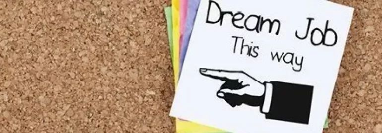 Notiz mit der Aufschrift 'Dream Job this way' und einem Pfeil nach rechts zeigt auf einem Korkbrett.