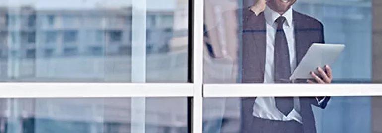 Ein Geschäftsmann steht in einem Bürogebäude und telefoniert.