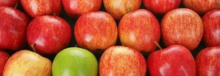 Mehrere rote Äpfel mit einem grünen Apfel dazwischen.