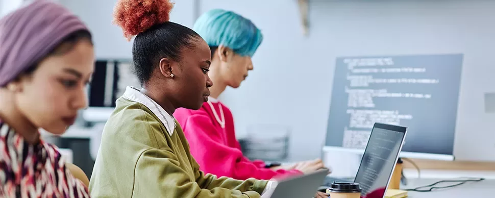 Drei Personen arbeiten an Laptops in einem modernen Büro.