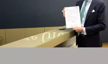 Mann in Anzug hält ein Dokument vor dem Page Group Logo.