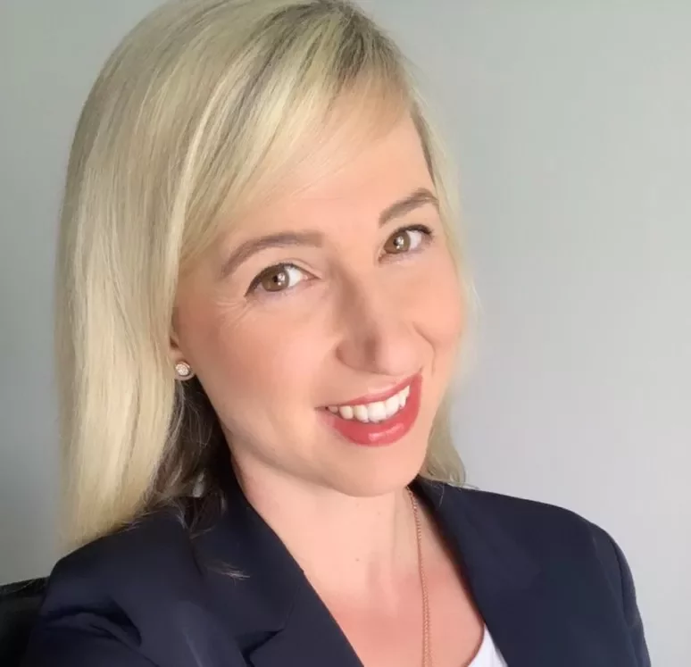 Frau mit blondem Haar und dunklem Blazer lächelt