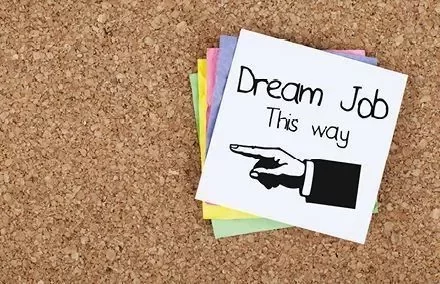 Notiz mit der Aufschrift 'Dream Job this way' und einem Pfeil nach rechts zeigt auf einem Korkbrett.