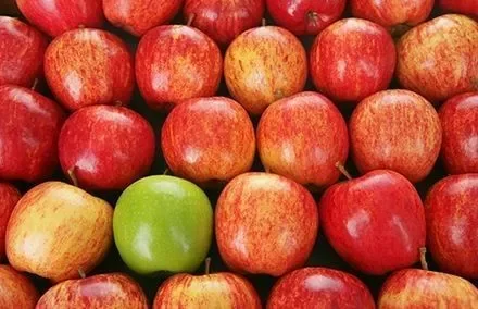 Mehrere rote Äpfel mit einem grünen Apfel dazwischen.